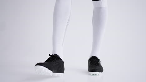 young-afro-american-football-player-is-playing-with-ball-in-studio-closeup-of-feet-and-full-length